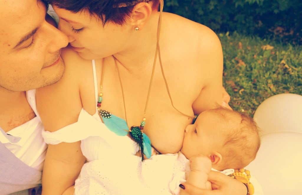 Elternpaar mit stillendem Baby an der Brust | Attachment Parenting