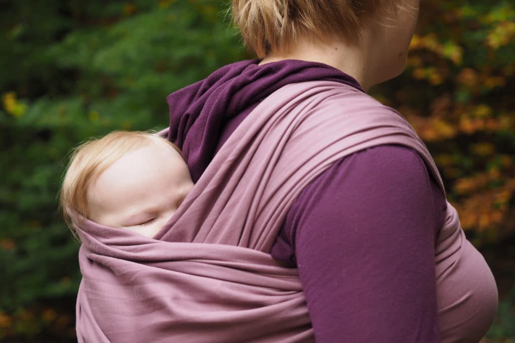 Mother wearing her baby in a wrap on her back