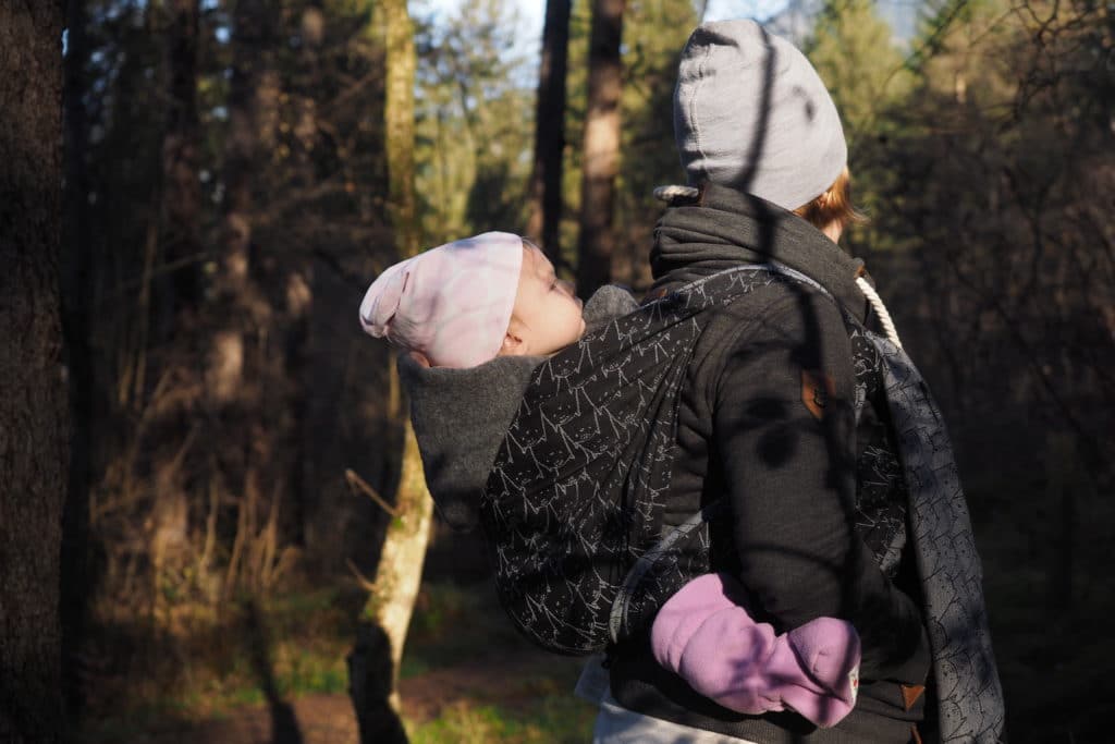 babywearing mama with baby on her back in the forest