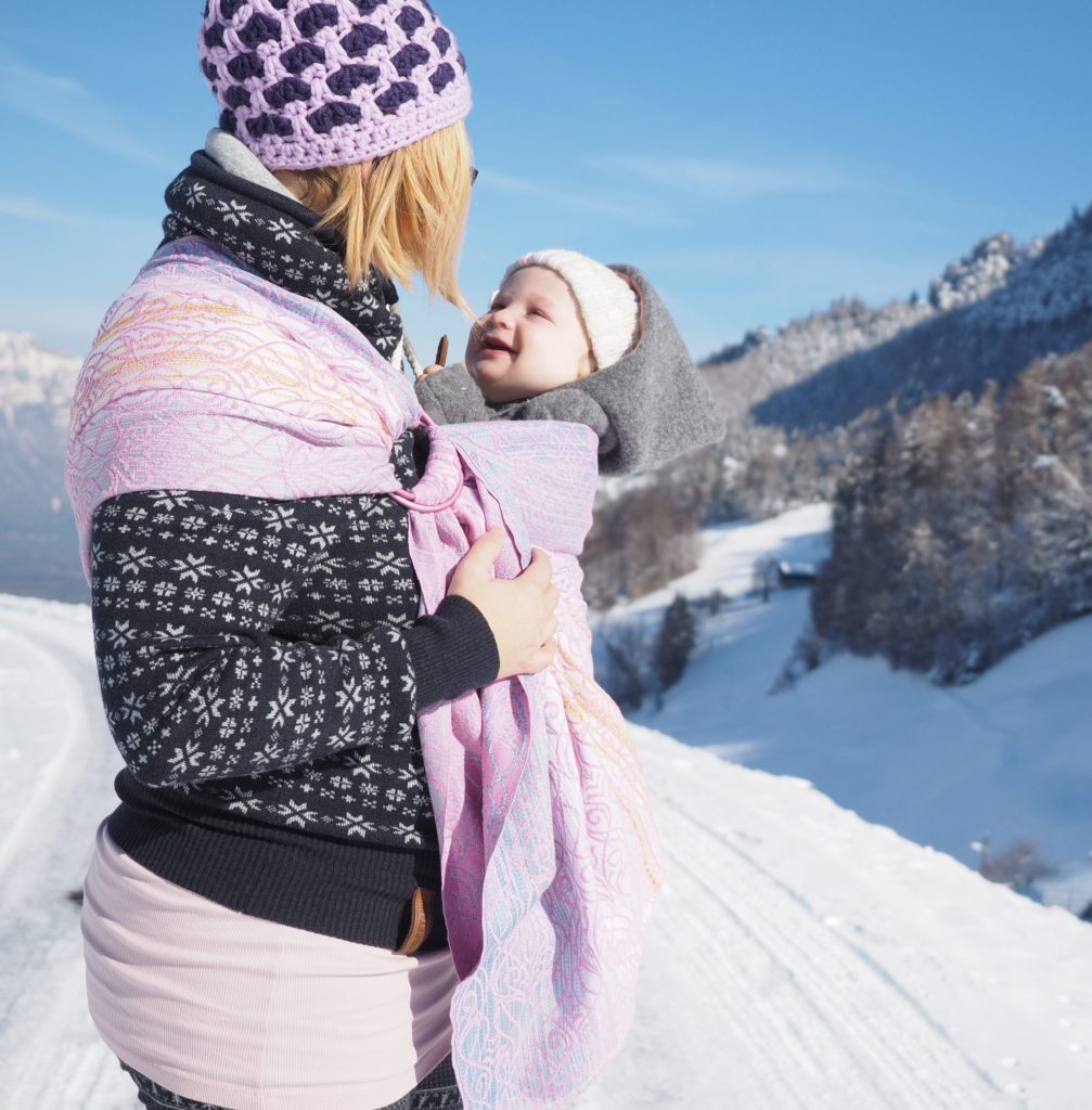Tragemama mit Baby im Ring Sling vor Schneelandschaft